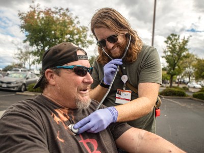 Dr. Kyle Patton checks the heartbeat of one of his patients, William, while in a Raley’s grocery store parking lot in northwest Redding on Sept. 19, 2022. Photo by Larry Valenzuela, CalMatters/CatchLight Local